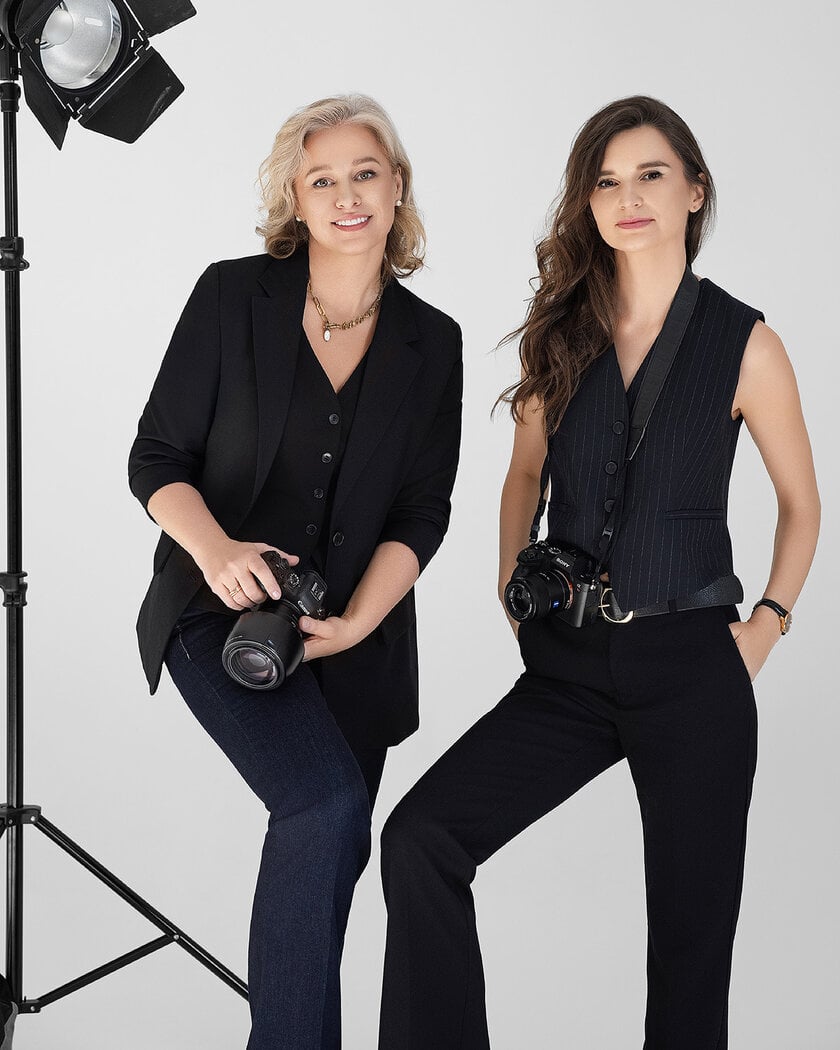 Fotografės Deimantė ir Rasa iš „Subtilūs vizualai“ pozuoja studijoje su fotoaparatais rankose – spalvota kūrybinė portretinė fotosesija Vilniuje.