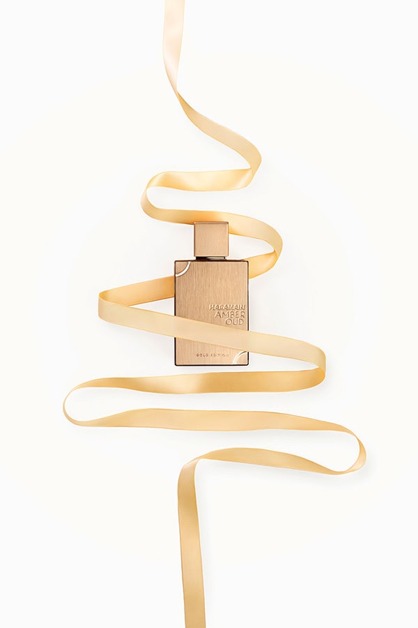 Produktų fotografija studijoje „Subtilūs vizualai“ – „Haramain Amber Oud Gold Edition“ kvepalai su aukso juostele baltame fone.
